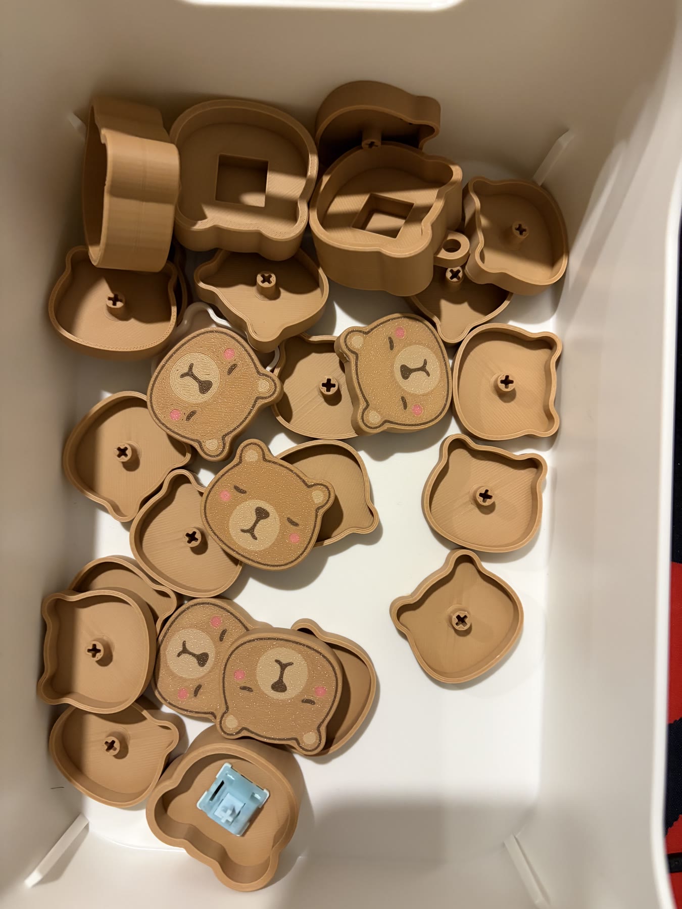 A bin of printed clicker parts used for repeated fitting tests and iteration.